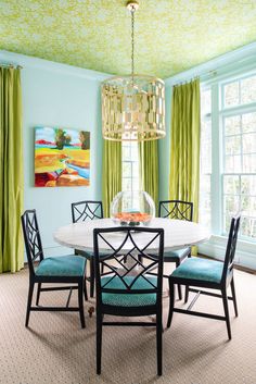 a dining room table with four chairs and a chandelier hanging from the ceiling