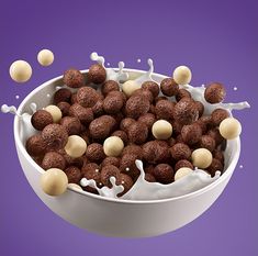 a bowl filled with chocolate balls and milk splashing out of it's top