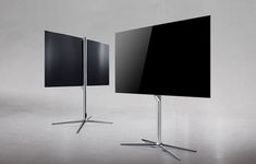 two televisions sitting next to each other in front of a gray wall and floor