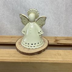 an angel figurine sitting on top of a piece of wood