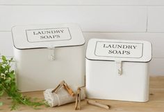 two laundry soap dispensers sitting on top of a wooden table