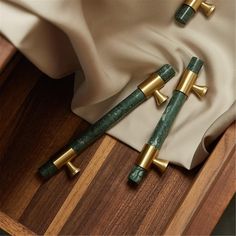 three green and gold crosses on top of a wooden table next to a white cloth