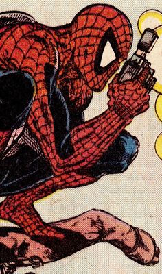 the spider - man is sitting down and looking at his cell phone while holding it in one hand