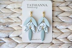 two pairs of blue and white earrings on top of a woven tablecloth with the tag tahitianana