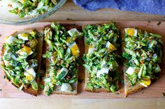 four slices of bread with vegetables and cheese on them next to a bowl of salad