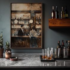 a painting hanging on the wall above a bar with liquor glasses and bottles in front of it