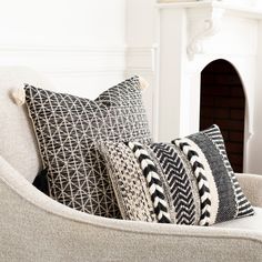 four pillows on a couch in front of a fireplace