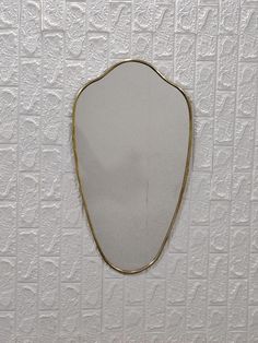 a white wall with a mirror hanging on it's side and a gold frame