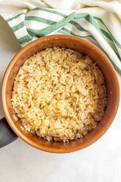 a bowl filled with brown rice sitting on top of a white counter next to a green and white towel