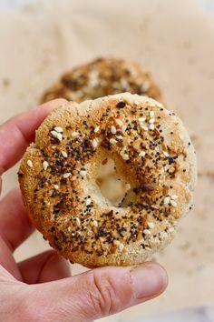 two bagels with sesame seeds are being held up