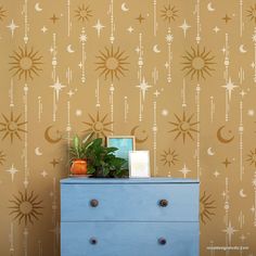 a blue dresser sitting next to a wall with stars and moon stencils on it