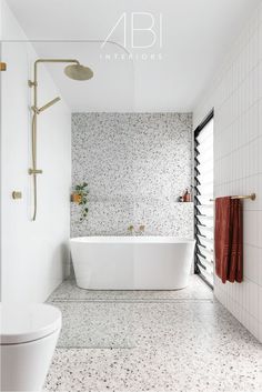 a white bath tub sitting next to a toilet in a bathroom