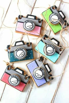 four different colored camera ornaments hanging from twine