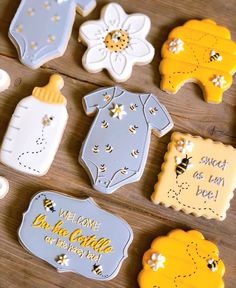 baby shower cookies are arranged on a wooden table with the words welcome little one in yellow and white