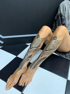 a woman sitting on the floor with her legs crossed and tattoos on her leg,