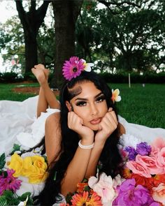 a woman laying on the grass with flowers in her hair