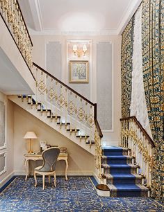 an elegant staircase with blue carpet and white walls