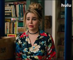 a woman sitting in front of a bookshelf