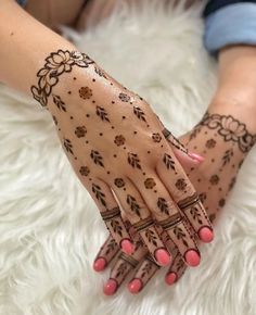 a woman's hands with hennap on it and pink nail polishes