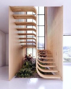 a spiral staircase in the middle of a room with plants on the floor and large windows