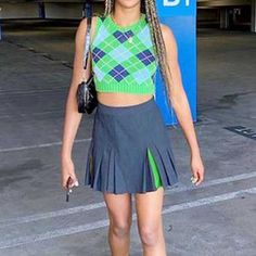 a woman with braids in a green and blue top is standing on the tarmac