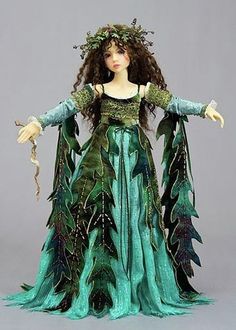 a doll is dressed in green and has leaves on her head, holding a snake