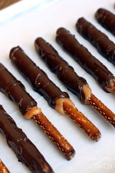 chocolate covered pretzels are lined up on a sheet of white paper with caramel drizzle