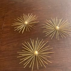 three gold pins sitting on top of a wooden table