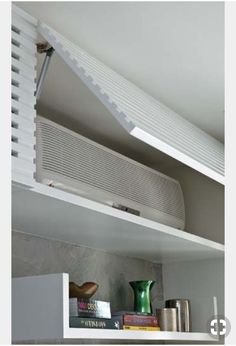 an air conditioner sitting on top of a white shelf next to a green vase