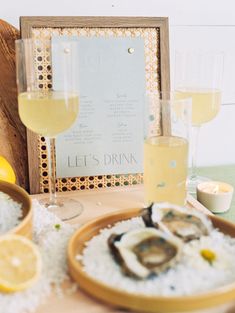 a table topped with oysters and rice next to glasses of wine in front of a sign