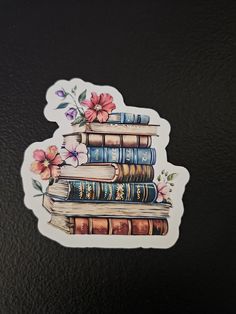 a sticker with books and flowers on it sitting on top of a black surface