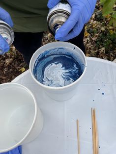 two people in blue gloves are holding cups