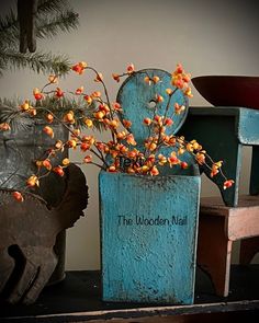 the wooden nail sign is next to a vase with flowers in it and an elephant figurine