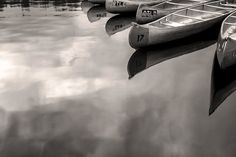 several canoes are lined up on the water's edge in black and white