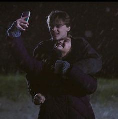 a man and woman standing in the rain taking a selfie with their cell phone