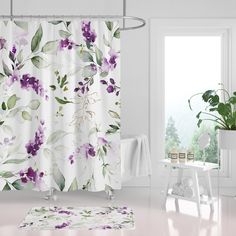 a white bathroom with purple flowers on the shower curtain