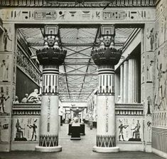 an old black and white photo of some columns in a building with egyptian paintings on the walls