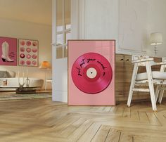 a pink record sitting on top of a hard wood floor next to a white chair