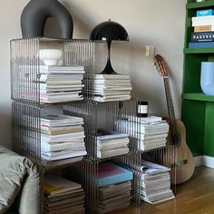 a stack of books sitting on top of a wooden floor next to a green book shelf