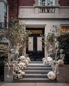 halloween decorations are on the steps in front of a building with black and white pumpkins