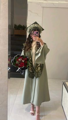 a woman taking a selfie in front of a mirror wearing a graduation cap and gown