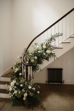 a staircase with white flowers and greenery on the bannister, next to a radiator