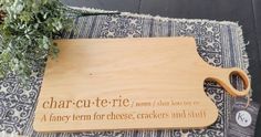 a wooden cutting board that says charcuterie on it next to a potted plant