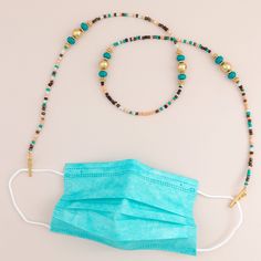 a blue face mask and beaded necklace on a white surface