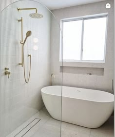 a white bath tub sitting under a window next to a shower head and faucet