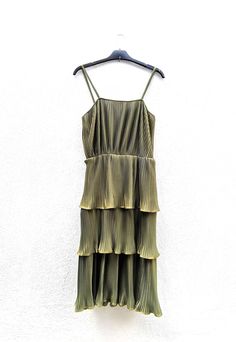 Amazing khaki green pleated dress from 1980's. Made by a Greek designer (Nanoka) of the time. Sleeveless dress with elasticity and spaghetti straps. Polyester pleated fabric of great quality that gives a metallic color feeling.  Comes with a rope belt.  No zipper. Has elastic inner linning.  Ideal for not so curvy/fit and flare silhouette. Feel free to contact us for further info regarding item details. DELIVERY TO GREECE: The service used is ELTA COURIER SERVICES. Items usually reach destinatio Charleston Dress, Vintage Green Dress, Spaghetti Straps Dress, Glam Dress, Disco Glam, Straps Dress, Rope Belt, Dress Pleated, 1980s Dresses