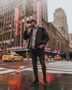 a man standing in the rain drinking from a bottle