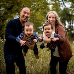 three adults and two children are posing for a photo in the grass with trees behind them