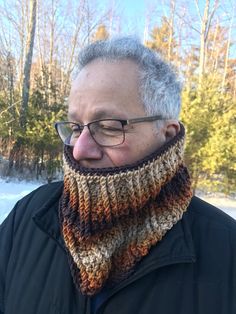 an older man wearing glasses and a knitted cowl neckwarf in the snow