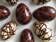 chocolate covered eggs with white and brown swirls on them sitting on a plate in the shape of an egg